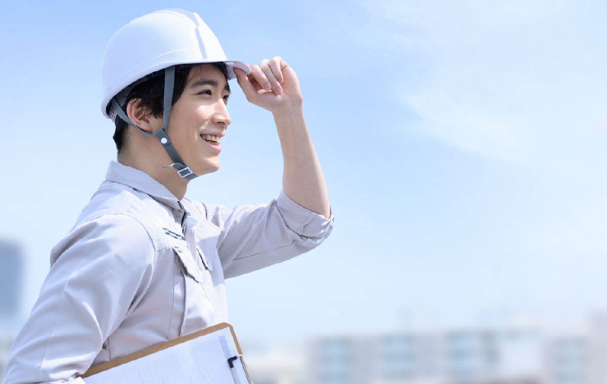 ヘルメットを被り笑顔で現場を見つめる作業員